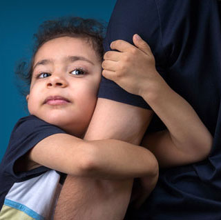 child clinging to parent's arm