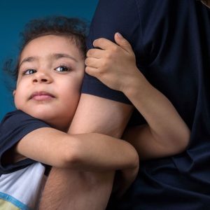 child clinging to parent's arm