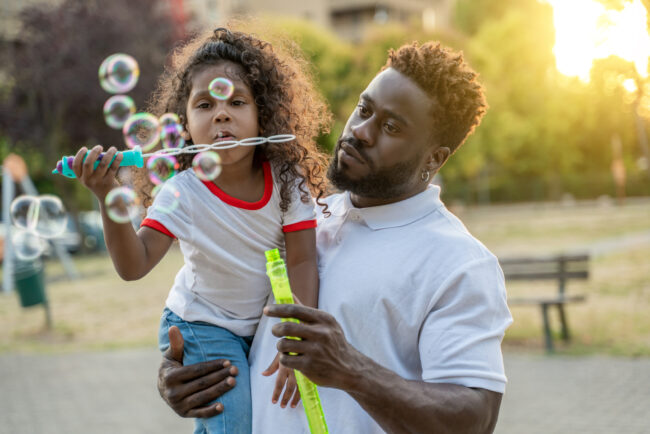 dad and girl blowing bubbles outdoors