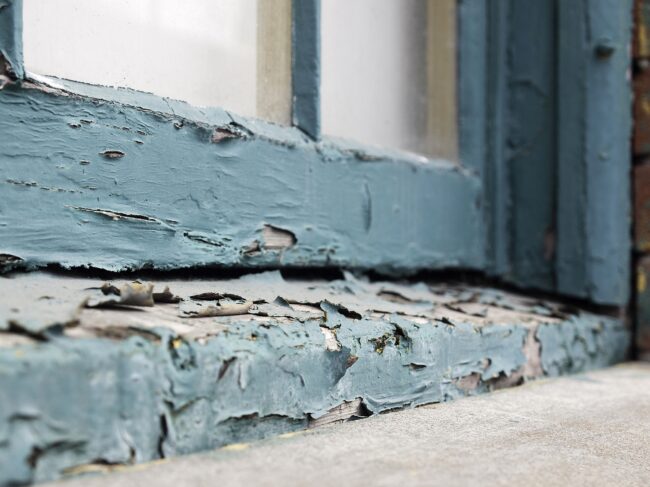 Closeup of an old window sill with paint peeling and flaking off